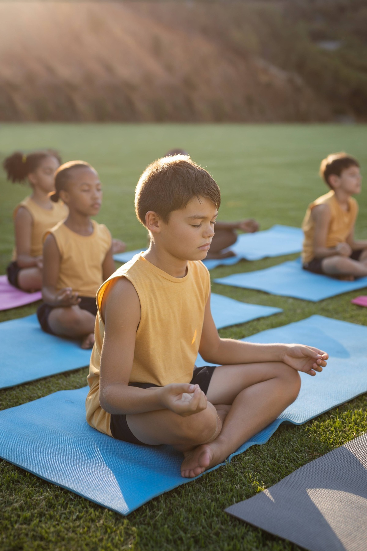 caucasian-boy-practicing-yoga-meditating-sitting-yoga-mat-garden-school(1)(1)