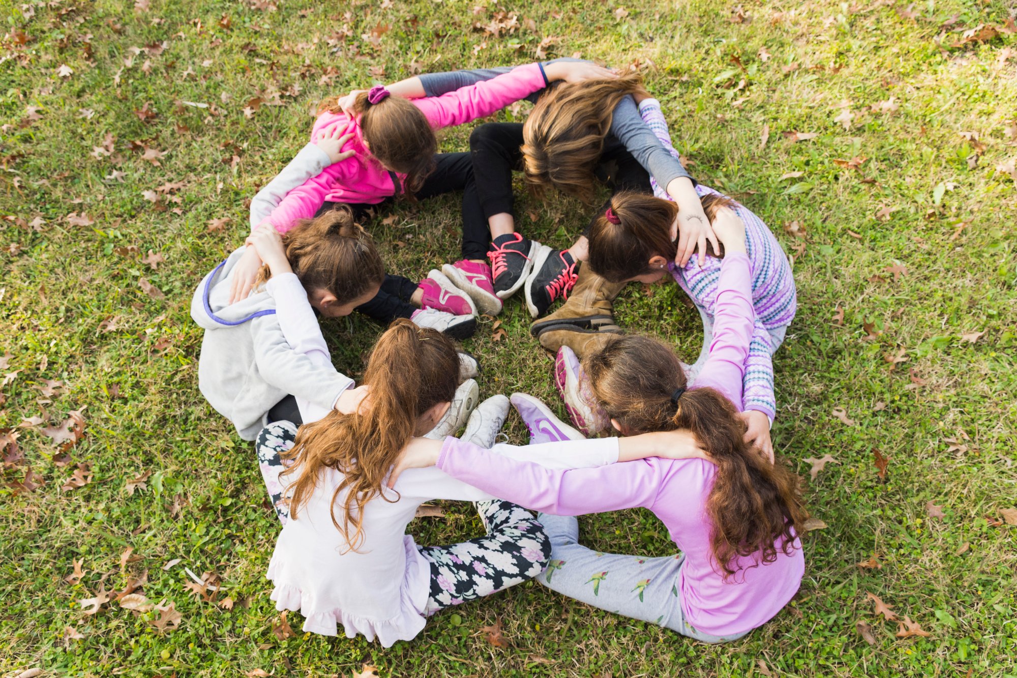 group-girls-sitting-together-huddle-green-grass